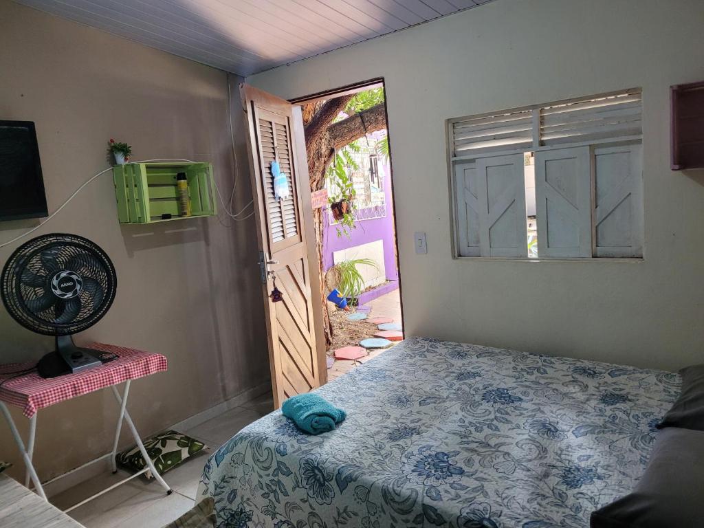 a bedroom with a bed and a door with a fan at Hostel Margo in Natal