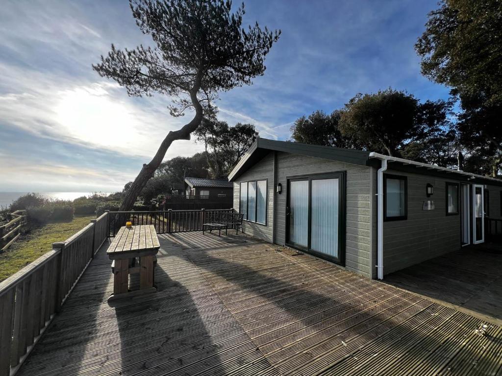 a small house on a wooden deck with a bench at Luxury Lodge With Full Sea Views At Azure Seas In Suffolk Ref 32105og in Lowestoft