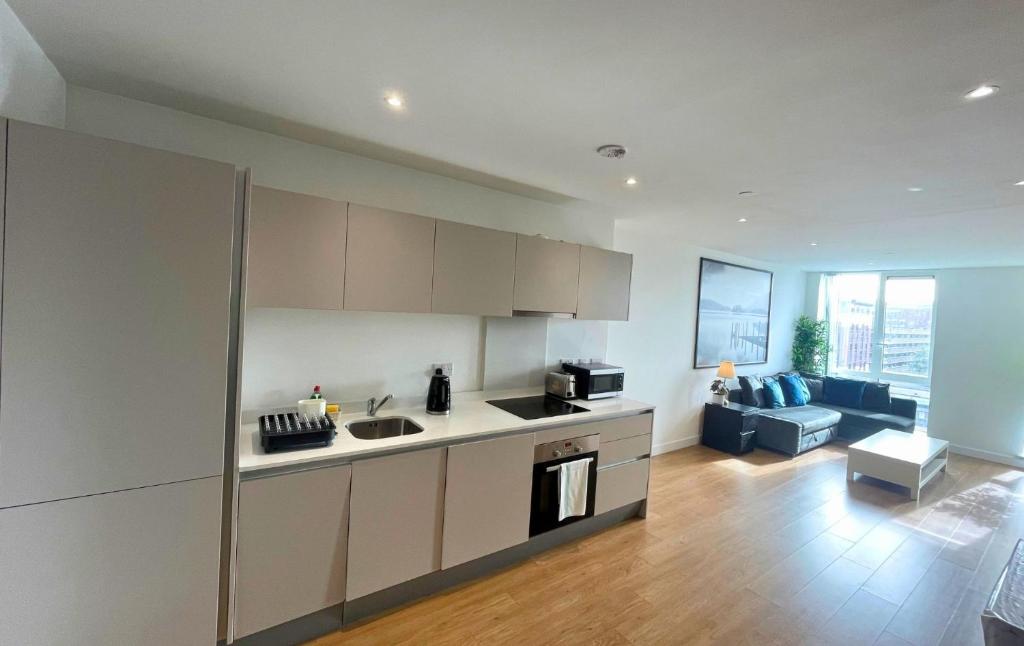 a kitchen and a living room with a couch at Bracknell Stylish Two Bedroom Apartment in Bracknell