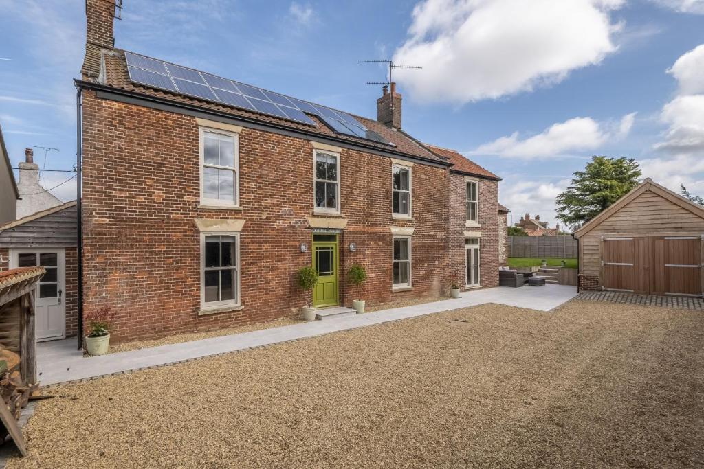 a brick house with solar panels on the roof at Old Mill House 6 in Brancaster