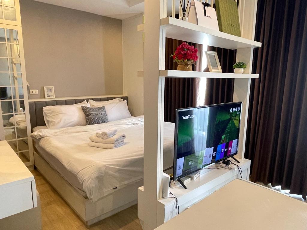 a bedroom with a bed with a television on a shelf at The Patio bangsaen miracle Seaview in Ban Bang Saen (1)