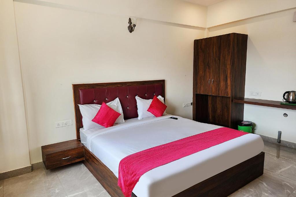 um quarto com uma grande cama branca com almofadas vermelhas em FabHotel KSP Kings Inn em Bangalore