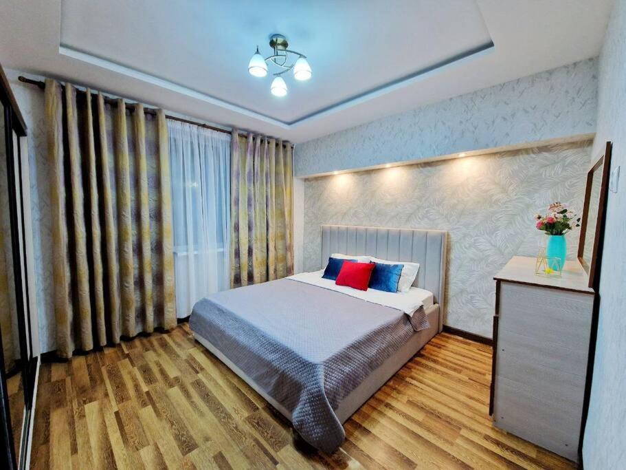 um quarto com uma cama grande com almofadas azuis e vermelhas em Просторная 3 комнатная квартира em Taraz
