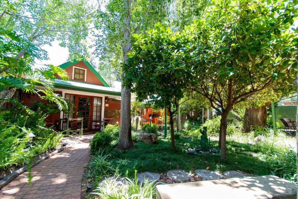 a home with trees and a brick walkway at Kleine Eden Guesthouse in Bloemfontein