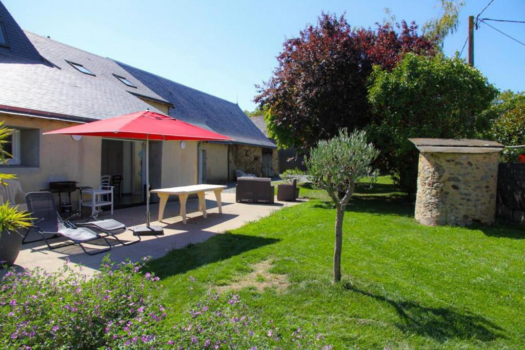un patio con una mesa y una sombrilla roja en Gîte du Pavement, en Craon