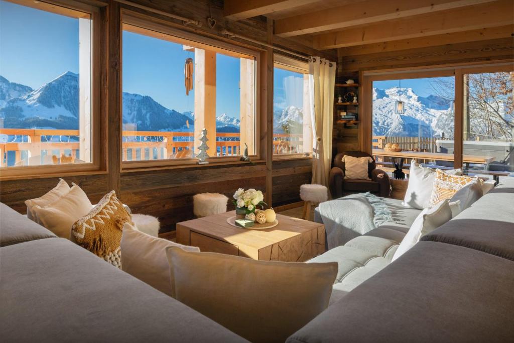 a living room with couches and windows with mountains at Chalet Serbijanka - OVO Network in Manigod