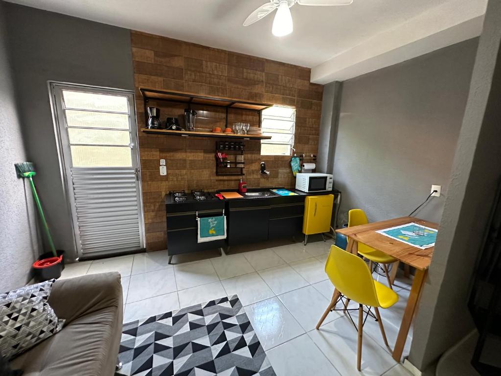 une cuisine avec un bureau et une table avec des chaises jaunes dans l'établissement Confortável Kitinete Duplex, à Fortaleza