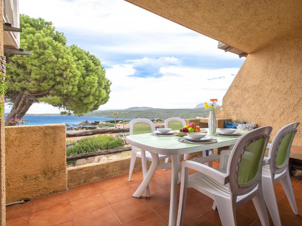 a white table and chairs on a patio with a view of the ocean at Apartment I-1-4 by Interhome in Golfo Aranci