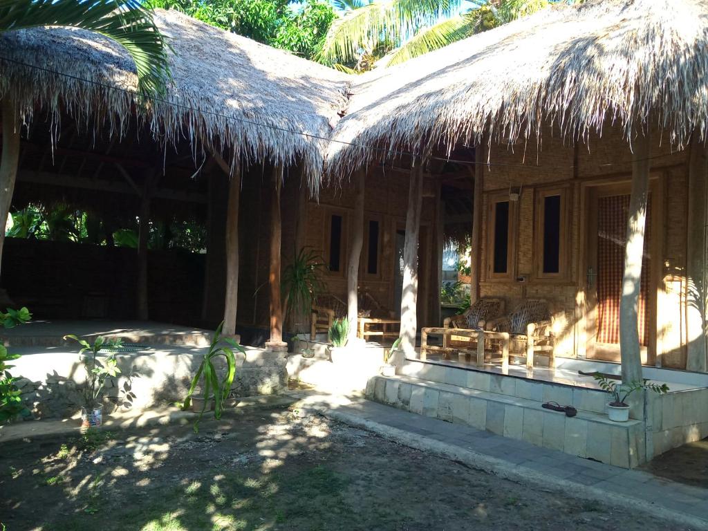 a house with a straw roof and a patio at Azka Homestay in Kuta Lombok