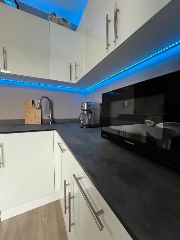 a kitchen with white cabinets and a black microwave at Modern Garden Studio for comfy stay in Luton
