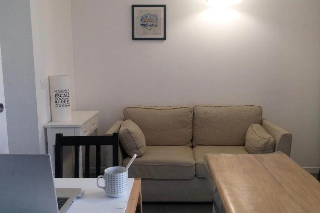 a living room with a couch and a table with a laptop at Appartment in a 16th-century castle in La Rochelle