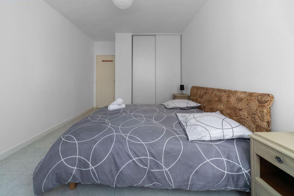 une chambre avec un grand lit avec une couette et des oreillers gris dans l'établissement Le Bardin - Grand appartement design, parking gratuit, à Vichy