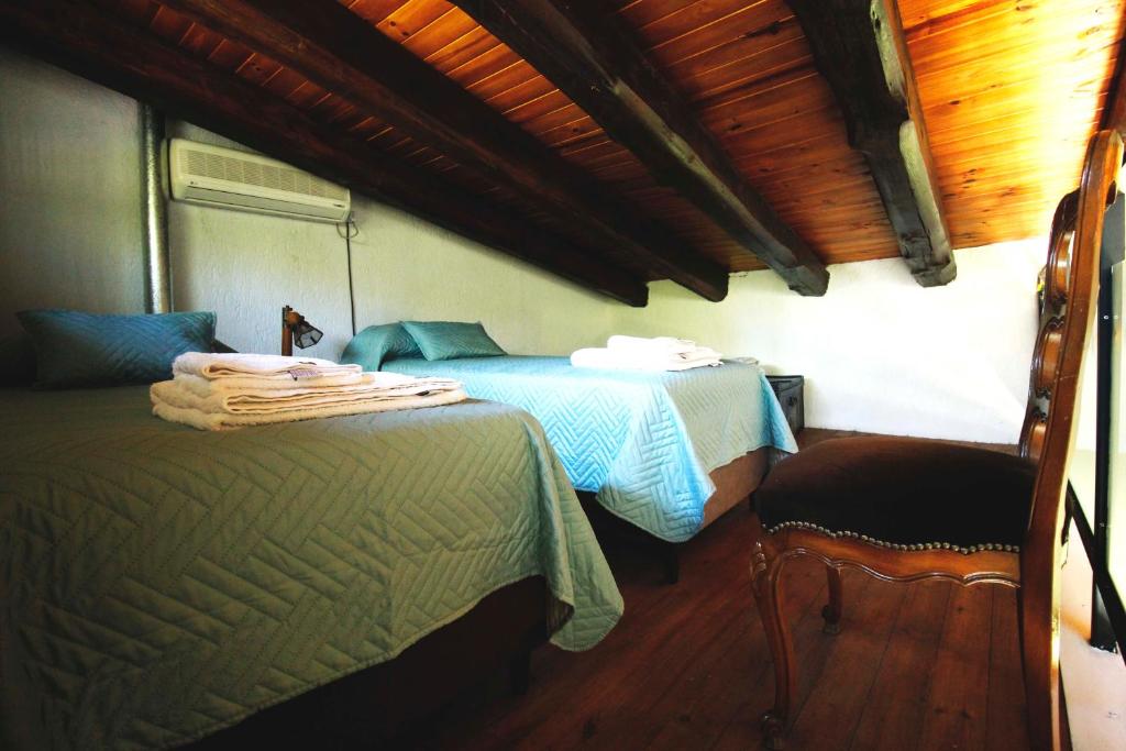 Un dormitorio con dos camas y una silla dentro. en Casa Encanto Uco, en Tunuyán