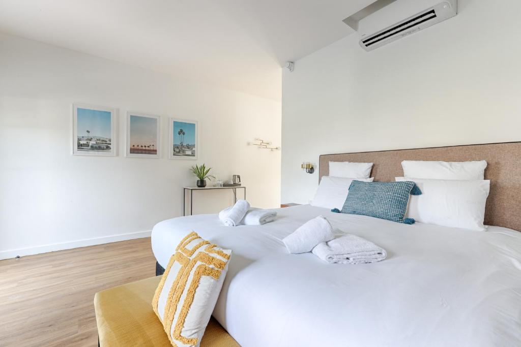 a white bedroom with two large white beds at La Coudraie - Proche de Disneyland in Montévrain