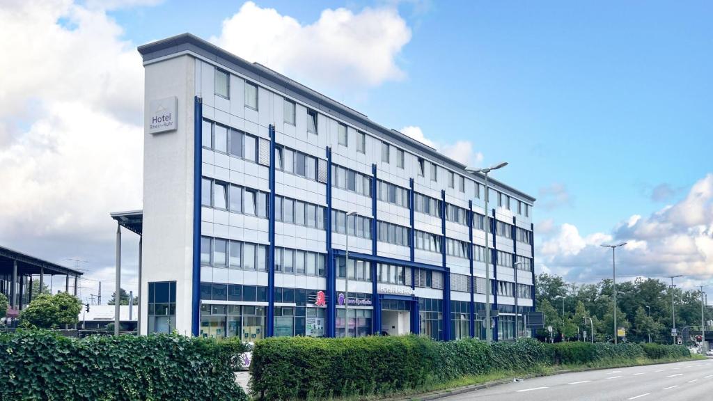 un edificio blanco con ventanas azules en una calle en Hotel Rhein-Ruhr Bottrop, en Bottrop