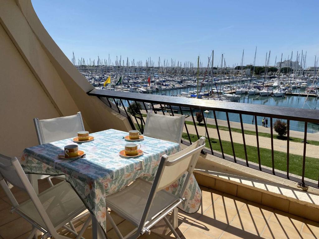 un balcon avec une table et des chaises et un port de plaisance dans l'établissement Appartement 2 pièces avec piscine et parking à Port Camargue - FR-1-250-113, au Grau-du-Roi