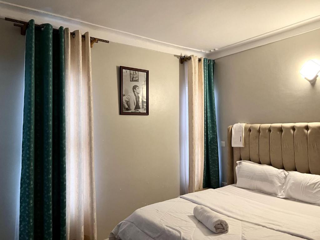 a bedroom with a bed and green curtains at Cyda Pearl Home-Buziga-Munyonyo in Kampala