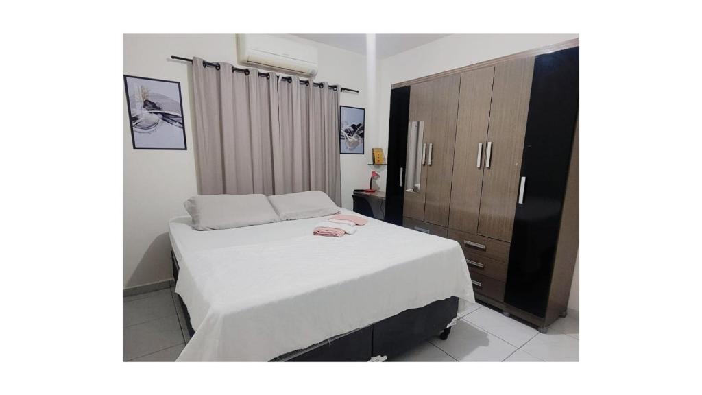 a bedroom with a white bed and a wooden cabinet at Apê Térreo, próximo ao Shopping! in Petrolina