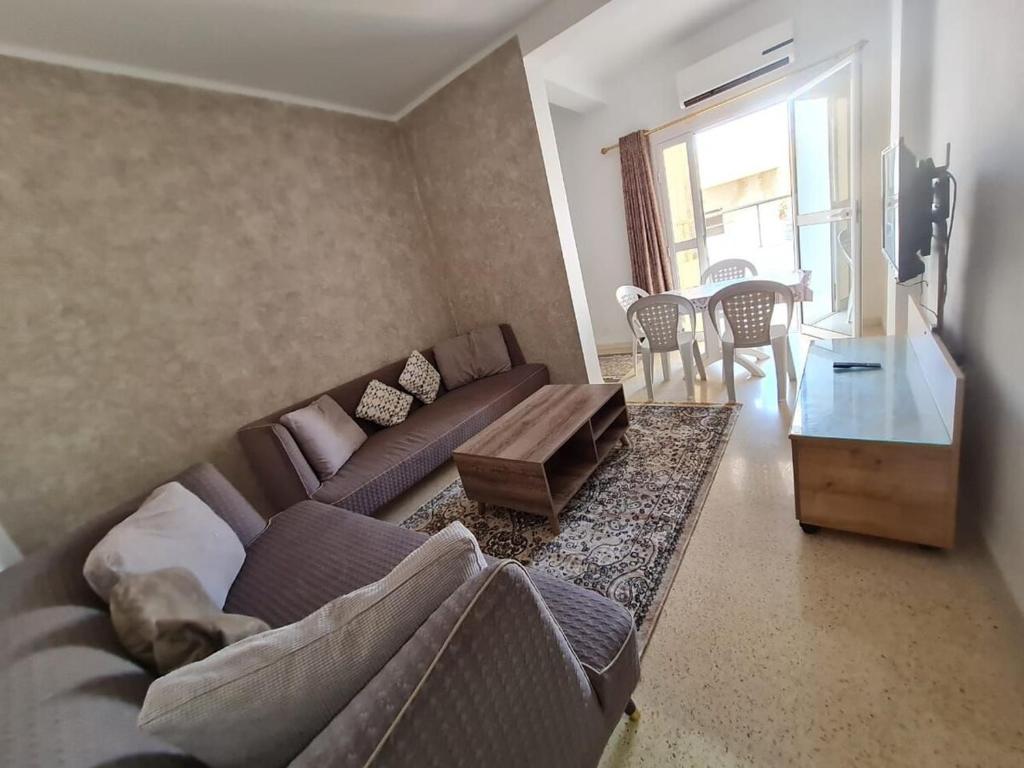 - un salon avec un canapé et une table dans l'établissement Bienvenue dans votre appartement, à Gabès