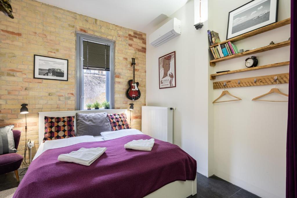 - une chambre avec un lit violet et un mur en briques dans l'établissement Paulay Deluxe studio, à Budapest