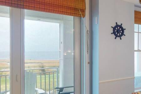 a clock on a wall next to a window at Sojourn Penthouse Sanctuary Condo 4 BR in Virginia Beach