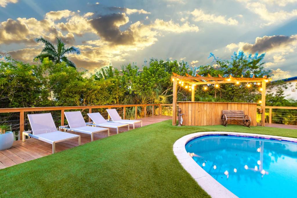 a backyard with a pool and chairs and a gazebo at Luxe Villa MiniGolf Pool FirePit in Aventura