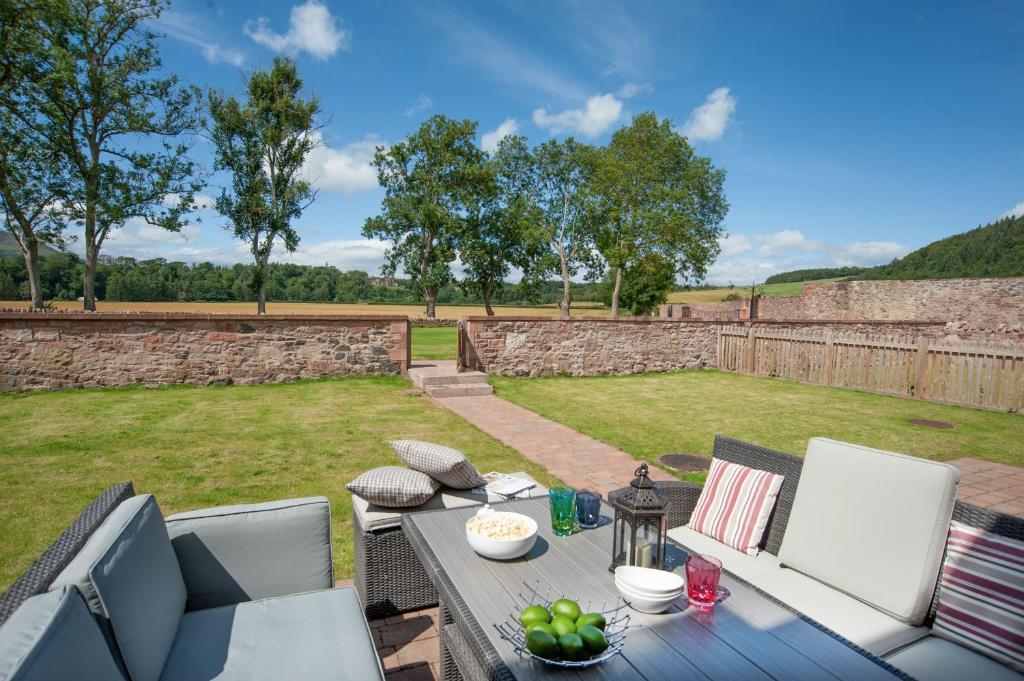 a patio with a table and chairs in a yard at Dryburgh Steading Two in Saint Boswells