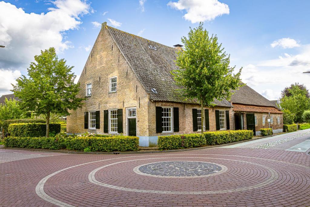a brick building with a clock in the middle of a road at Den Eijngel bed and breakfast in Boxtel