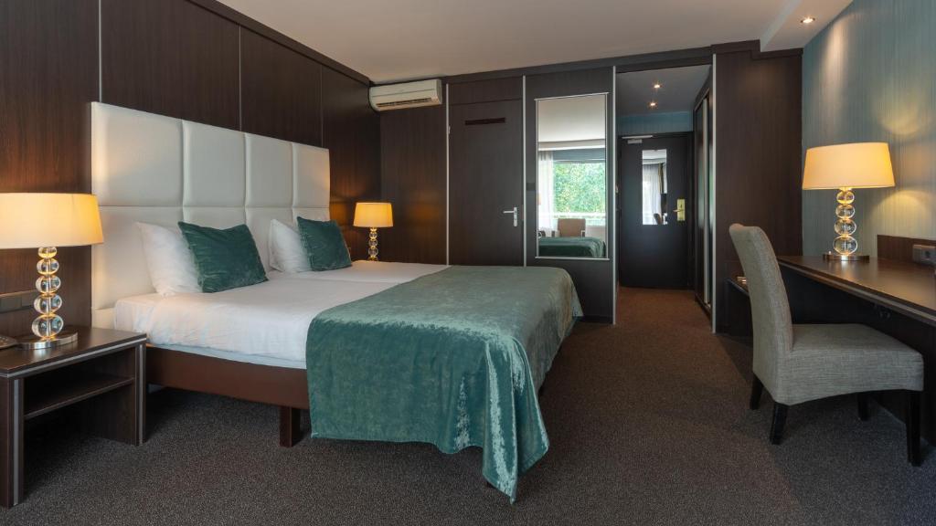 a bedroom with a large bed with a desk and a chair at Van der Valk Hotel 's-Hertogenbosch – Vught in Den Bosch