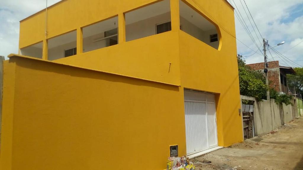 a yellow building with a white garage at casa pra muito gente in Tibau do Sul