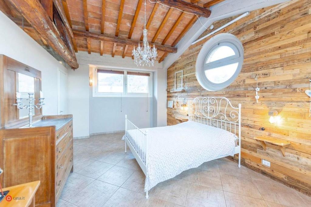 ein Schlafzimmer mit einem weißen Bett und einer Holzwand in der Unterkunft Casa Fevira Borgo in Borgo San Lorenzo