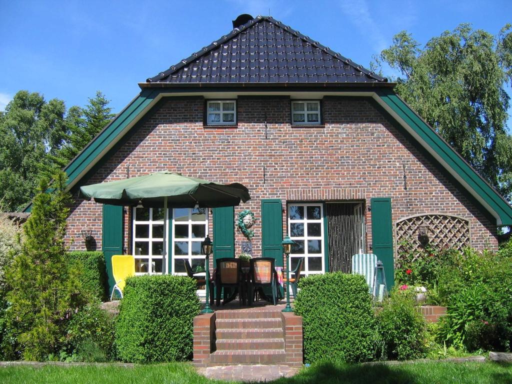 uma casa de tijolos com um guarda-chuva em frente em Landhaus Birkenhof, FeWo Vermittlung Nordsee 