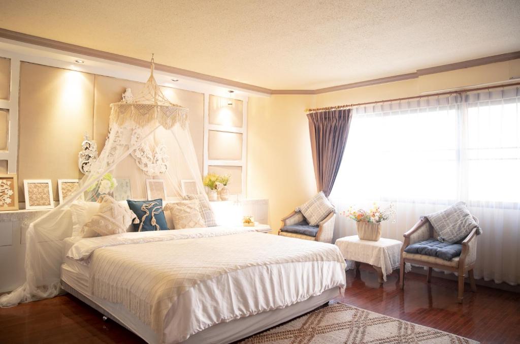 una camera da letto con un grande letto bianco e una finestra di Secret garden a Chiang Mai