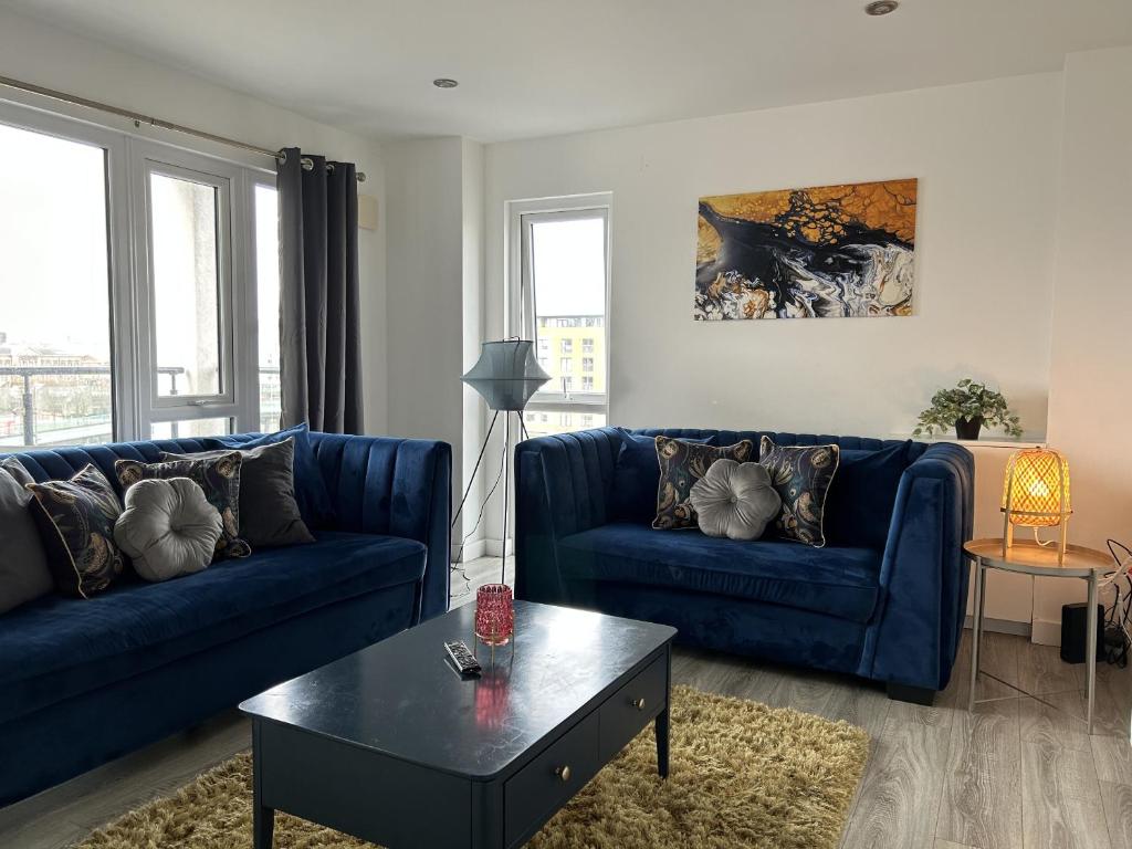 uma sala de estar com dois sofás azuis e uma mesa em Central Belfast Apartments Sandford em Belfast