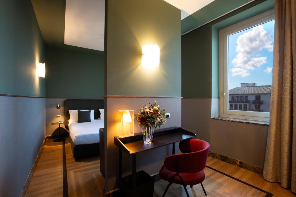 a hotel room with a bed and a desk and a window at Bianca Maria Palace Hotel in Milan