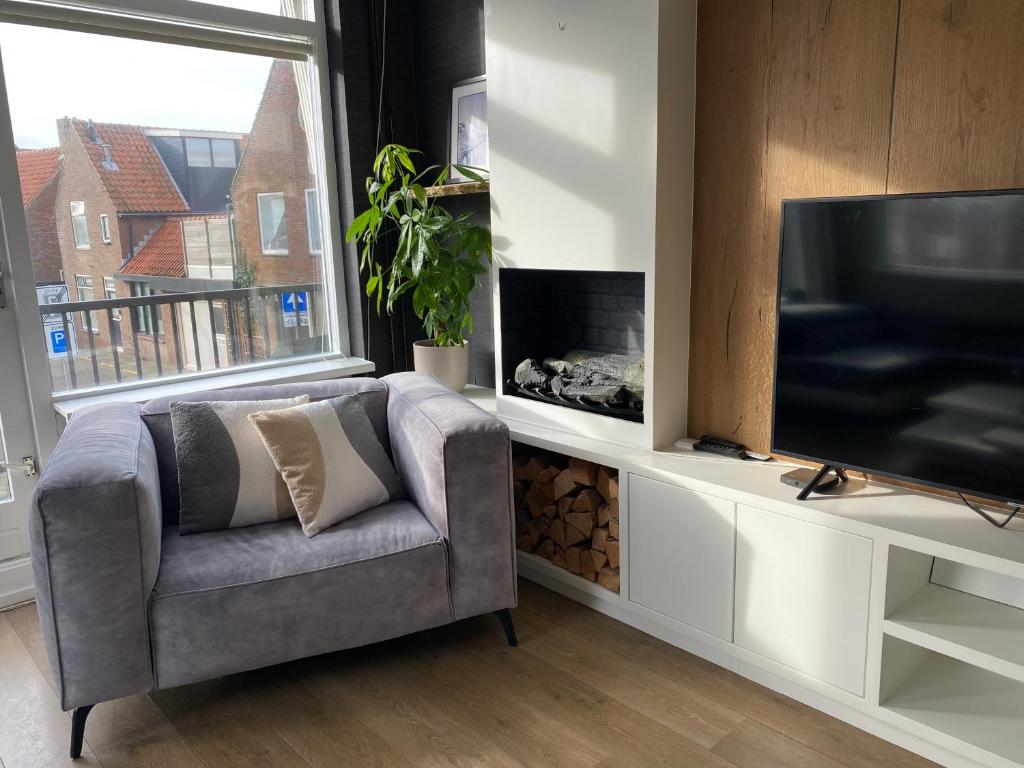 a living room with a chair and a television at Katwijk Center, 1 min away from the beach! in Katwijk aan Zee