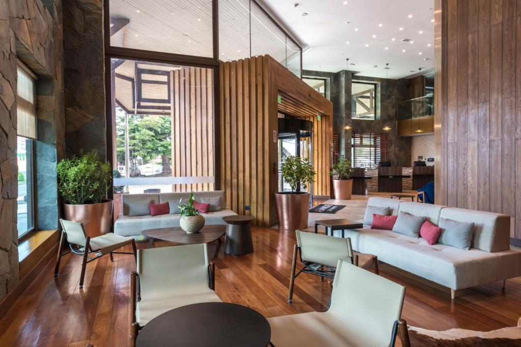 Courtyard by Marriott Puerto Montt في بويرتو مونت: غرفة معيشة مع أريكة وطاولات وكراسي