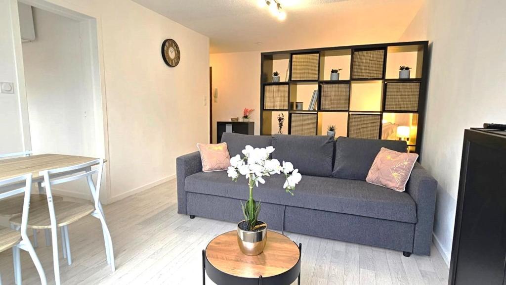 Una sala de estar con un sofá azul y una mesa. en Le Jude - studio - lumineux, en Vannes