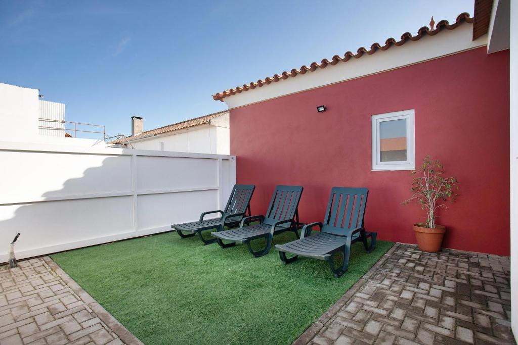 a group of chairs sitting on a lawn next to a wall at Casa Davó in Leiria