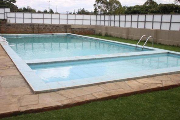 uma grande piscina num quintal com relva em Lux Suites Milimani Executive Apartments Nakuru em Nakuru