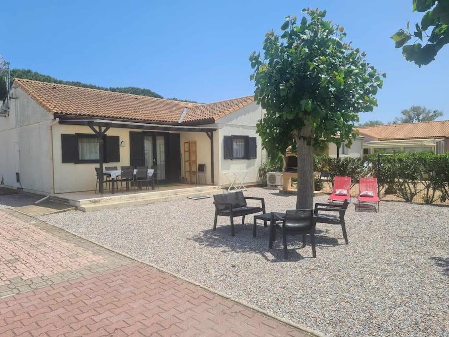 un patio avec des chaises et un arbre en face d'une maison dans l'établissement Maisonnette 4/6p. piscines toboggans et plage 200m, à Portiragnes