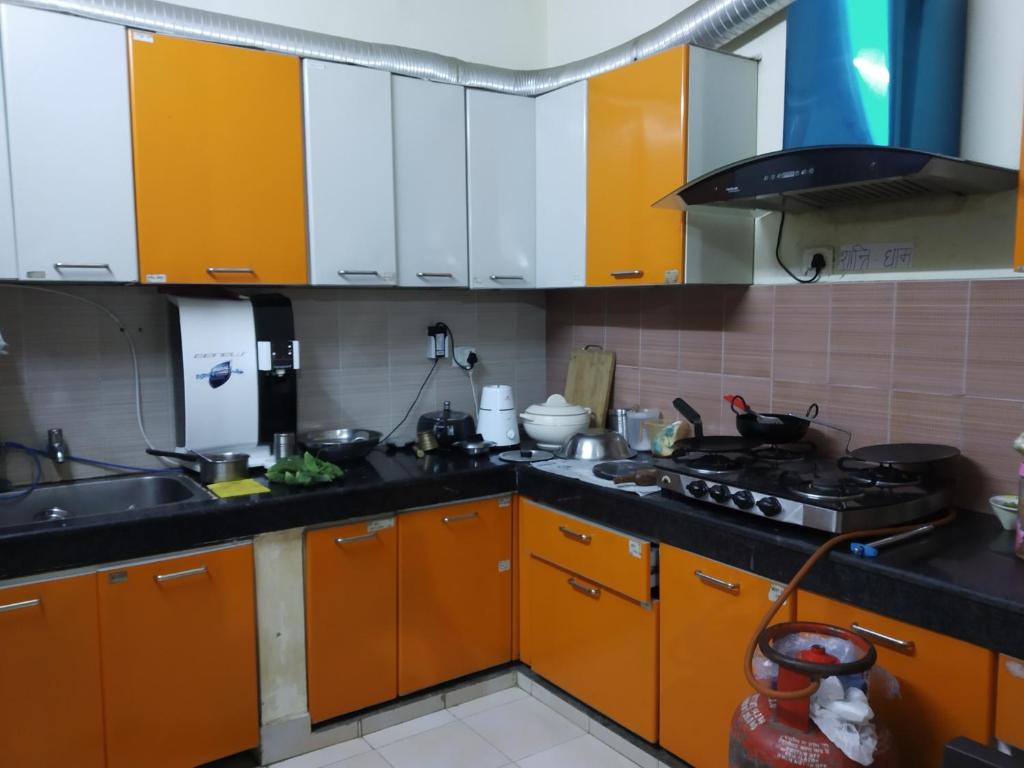 eine Küche mit orangefarbenen und weißen Schränken und einem Herd in der Unterkunft The Kashi Inn - Near Assighat in Upal