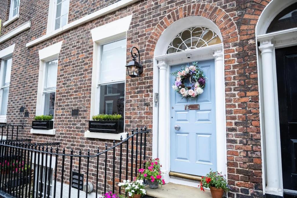 uma casa de tijolos com uma porta azul com uma coroa de flores em Liverpool Georgian Quarter Townhouse Rodney St em Liverpool