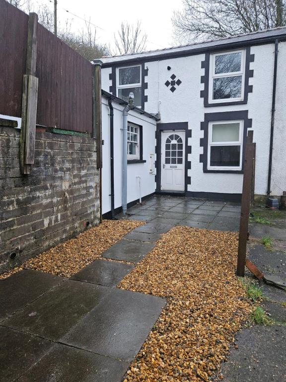 a white and black house with a driveway at Cwmynyscoy Cottage Pontypool NP4 5SQ in Pontypool
