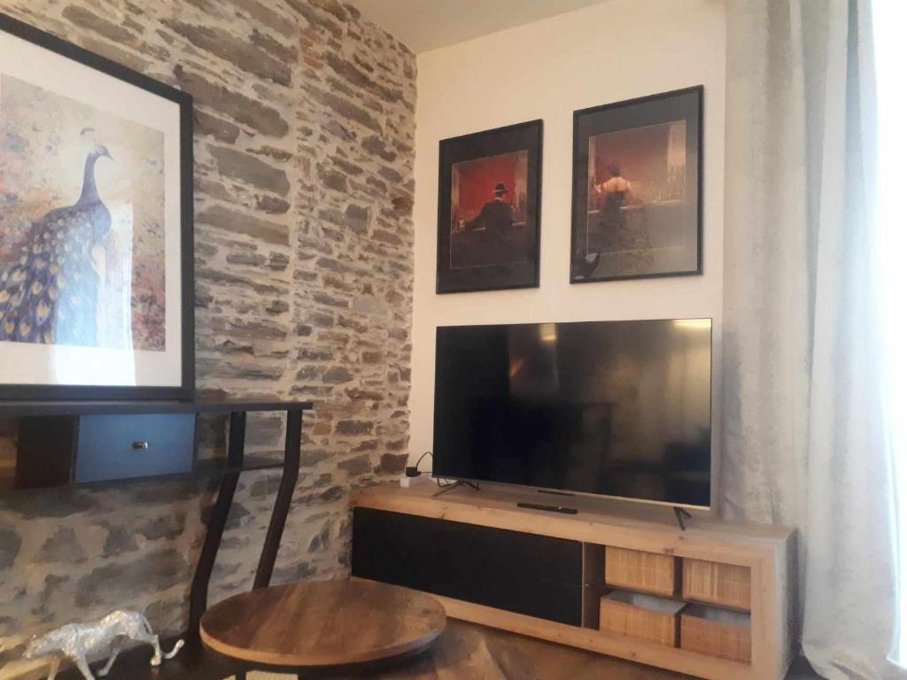 a living room with a television and a brick wall at LE SQUARE in Luchon