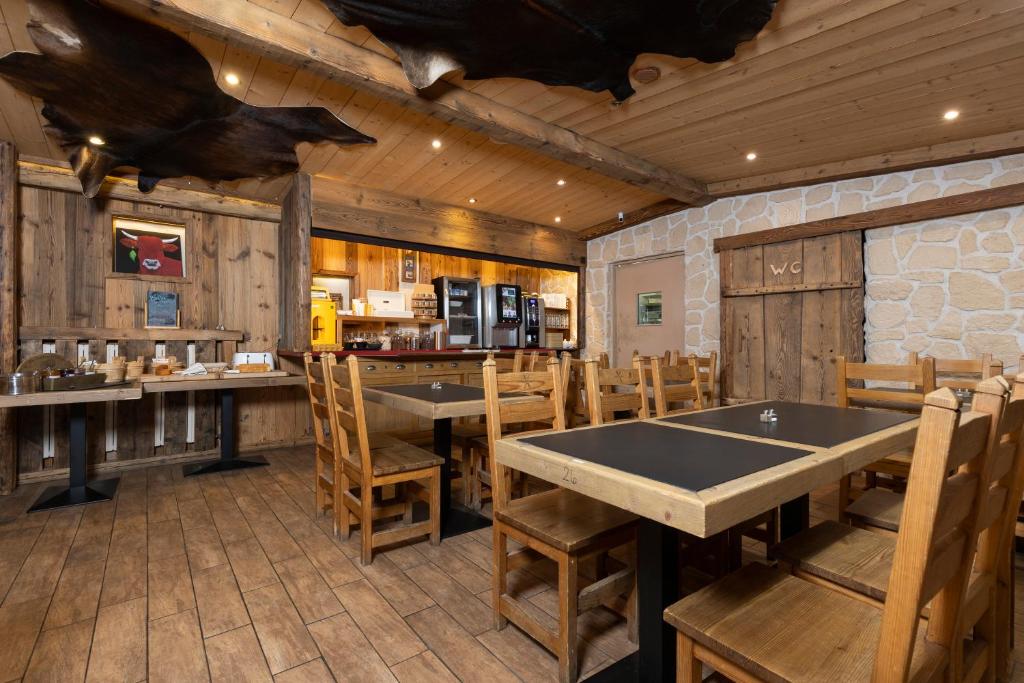 a dining room with tables and chairs and a kitchen at Le Saint Antoine in Les Houches