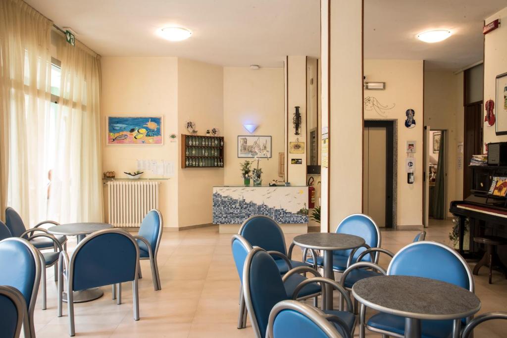 a room with tables and chairs and a piano at Hotel B&B Gladys in Cesenatico