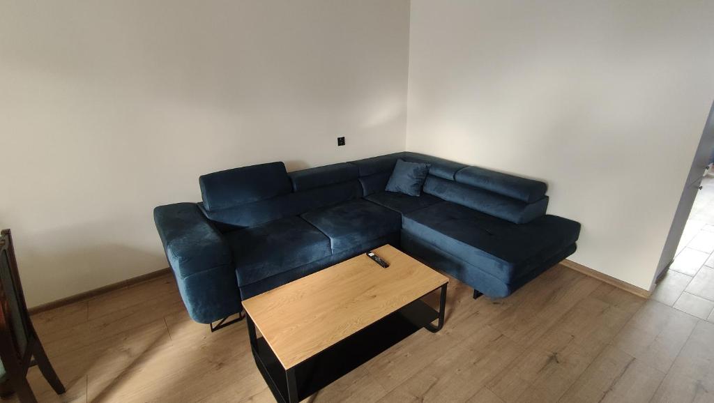 a blue couch in a living room with a wooden table at Mieszkanie Iława stare miasto in Iława