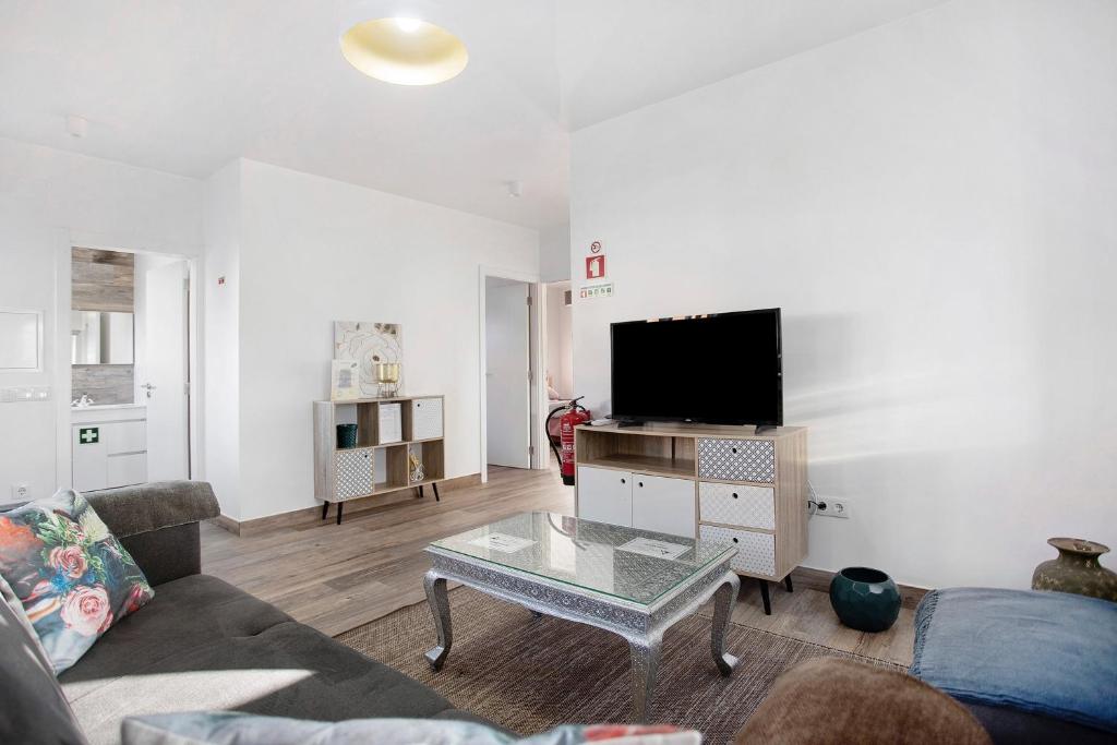 a living room with a couch and a flat screen tv at Casa da Padaria in Leiria