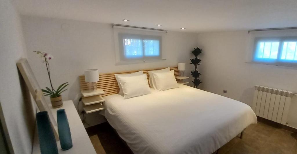 1 dormitorio con 1 cama blanca grande y 2 ventanas en Casita de Invitados con entrada privada, piscina y aire acondicionado, en Valdemorillo